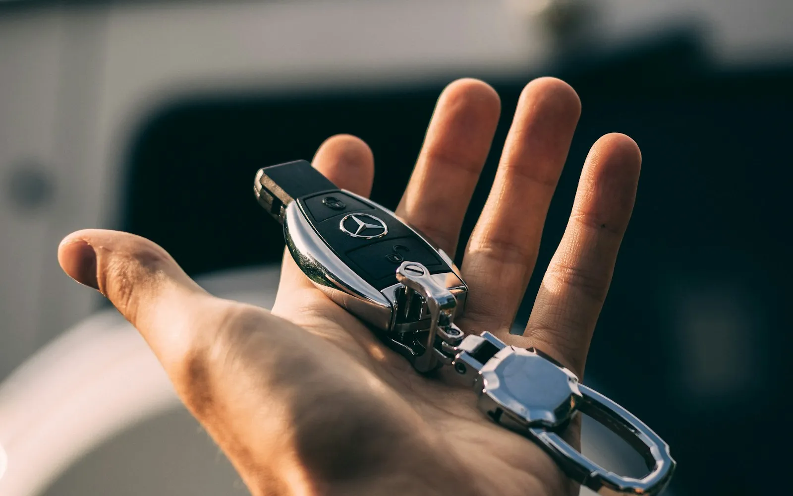 Clé de voiture remise dans une main devant un véhicule